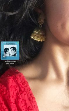 a woman in a red dress with gold earrings on her head and an image of elvis presley behind her ear