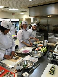 four chefs are in the kitchen preparing food