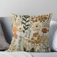 an embroidered pillow with flowers and leaves on it