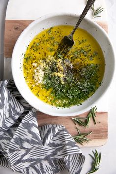 a white bowl filled with yellow soup on top of a wooden cutting board