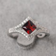 a ring with a red stone surrounded by white diamonds