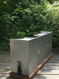 a concrete structure sitting on top of a wooden platform in front of some green trees