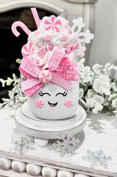 a white cup with pink bows and candy canes on it sitting on top of a table