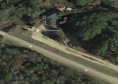 an aerial view of a road in the middle of some trees and land with houses on it