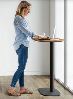 a woman standing at a table with her laptop on top of it and touching the screen