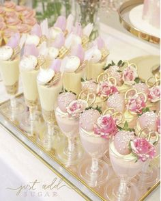 there are many desserts on the table with pink flowers in vases next to each other