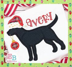 a black dog wearing a santa hat with the word avery on it's chest