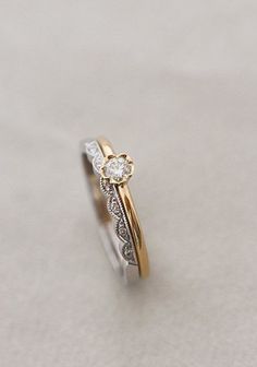 two tone gold and silver wedding ring with diamond accents on the side, set against a plain white background