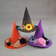 three small witches hats with flowers and feathers on them, one has a sunflower in the center