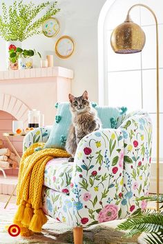 a cat sitting on top of a chair in a living room next to a fire place