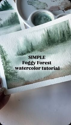 someone is holding up some watercolor paper with the words simple foggy forest on it