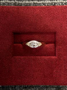 a diamond ring sitting on top of a red velvet box