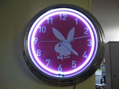 a neon clock with an image of a rabbit on it's face is hanging from the wall