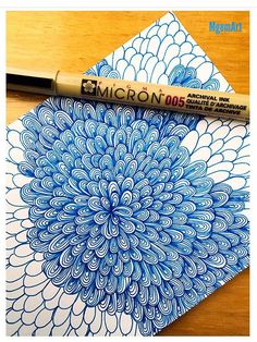 a pen is sitting on top of a drawing paper with an image of a blue flower