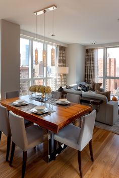 a dining room table and chairs in front of a large window with cityscape