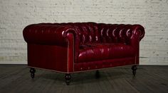 a red leather couch sitting in front of a white brick wall