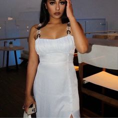 a woman in a white dress posing for the camera with her hand on her head