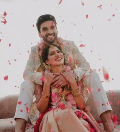 a man and woman sitting on top of a couch with petals falling all over them