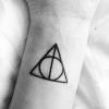 a small harry potter triangle tattoo on the wrist