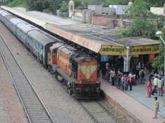 people are standing on the platform as a train pulls up to it's station