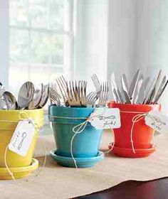 four pots with forks and spoons in them sitting on a table next to each other