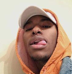 a man sticking his tongue out wearing an orange hoodie and jacket with the hood up