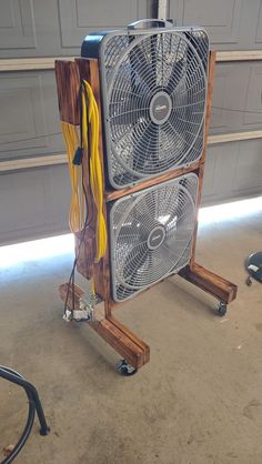 a large fan sitting on top of a wooden stand next to a garage door,