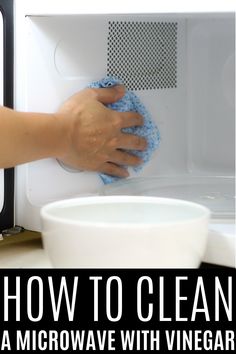 a person wiping up a microwave with a micro wave and a white bowl next to it