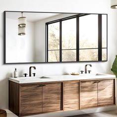 a bathroom with two sinks and a large mirror over it's face, in front of a window