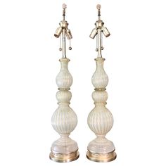 a pair of white glass candlesticks sitting on top of each other in front of a white background