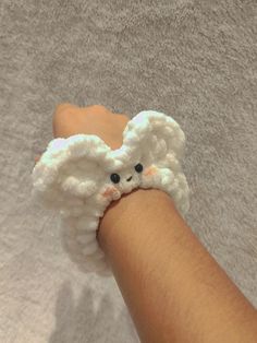 a hand is holding a small white stuffed animal