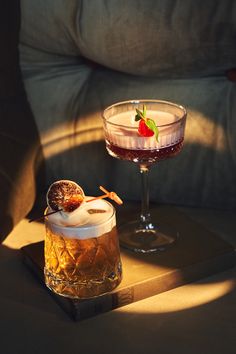 a drink in a glass on a table next to a book with a strawberries garnish