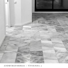 a black and white photo of a hallway with tile flooring in an apartment building