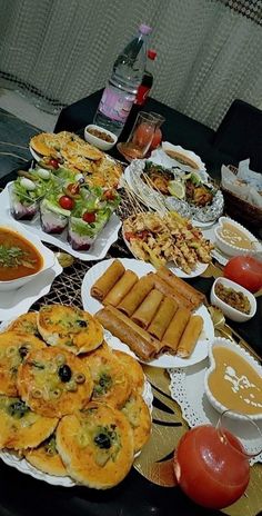 a table filled with lots of food on top of plates next to bowls and sauces