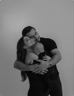 a man and woman hugging each other while holding a baby