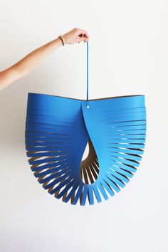 a person is holding up a blue paper fan that looks like a bird's nest