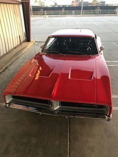 a red muscle car parked in a parking lot