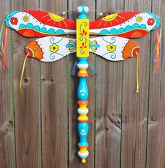 a brightly colored dragon statue on top of a wooden fence next to a wood fence