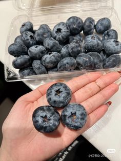 blueberries in a plastic container being held by someone