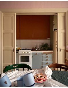 an open door leading to a kitchen with two cups on the table and food in front of it