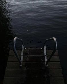 a boat dock with two metal railings on it's sides and water in the background