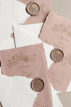 some pink and white envelopes with waxed seals on them are laying next to each other