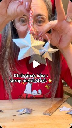 a woman holding up a paper star in front of her face with the caption christmas idea scrap metal stars