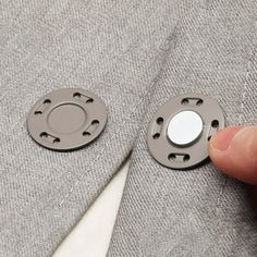 a person is cutting through the fabric with scissors and needle to make a button on a jacket