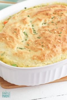 a casserole dish with cheese and vegetables in it on a wooden cutting board