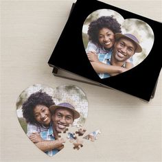 two heart shaped puzzles on a table next to a box with the same photo