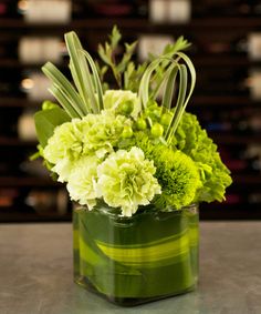 a vase filled with green flowers on top of a table