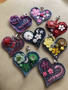 six heart shaped buttons with flowers and hearts attached to each one, all in different colors