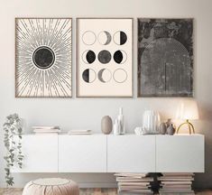 two black and white art prints hanging on the wall above a buffet with vases