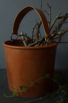 a potted plant with branches in it and a leather handle on the top, sitting on a table